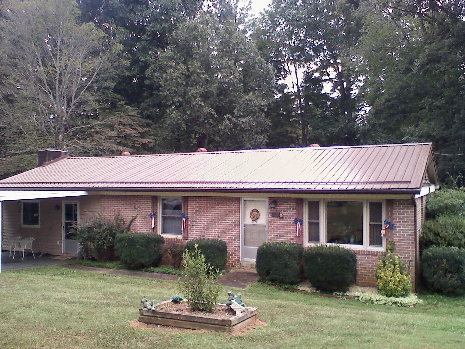 Bronze metal roof on a brick ranch home with a carport in Greenville