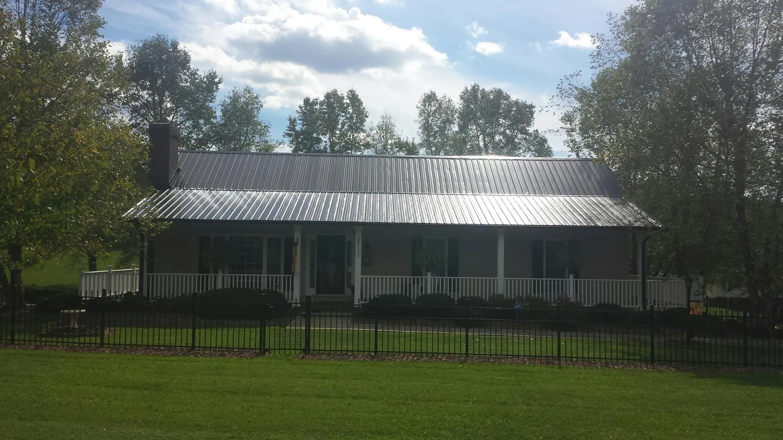 Gray metal roof on a brick ranch with a full width front porch — Gutter Guard Installation work by our crew in Greenville
